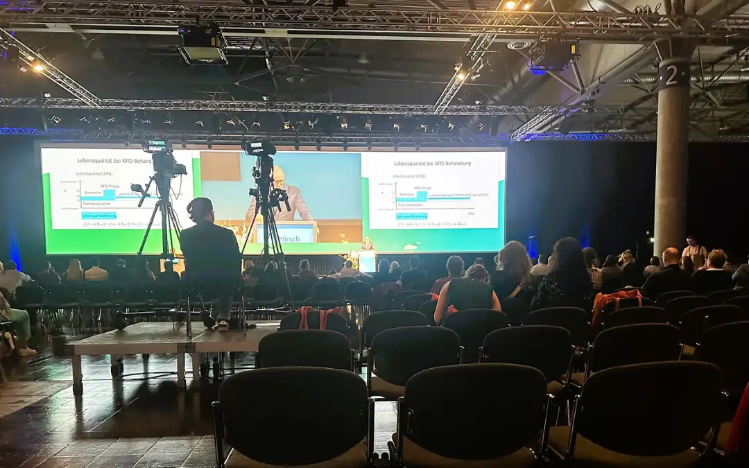 Vortragssaal der DGKFO 2025 mit Publikum und großen Leinwänden, Präsentation zum Thema Lebensqualität bei KFO-Behandlung.