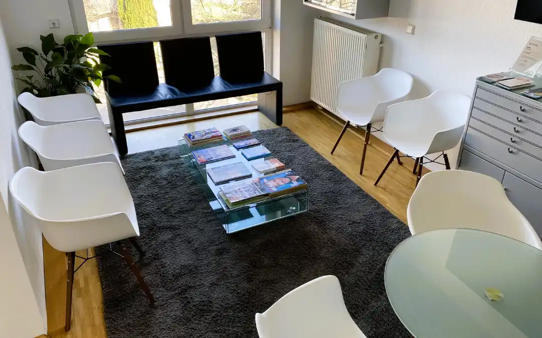 Wartezimmer der KFO Kaufhold mit bequemen Stühlen und Glastisch mit Zeitschriften
